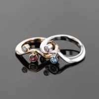 Rose and white gold wave shaped rings with diamonds and precious stones