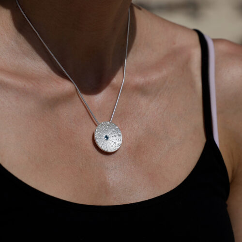 Disc shaped pendant in sterling silver with sea urchin patterns and a Blue Topas