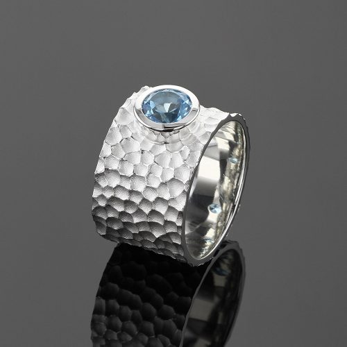 Wide silver ring with a lava rock texture and 6mm Blue Topas