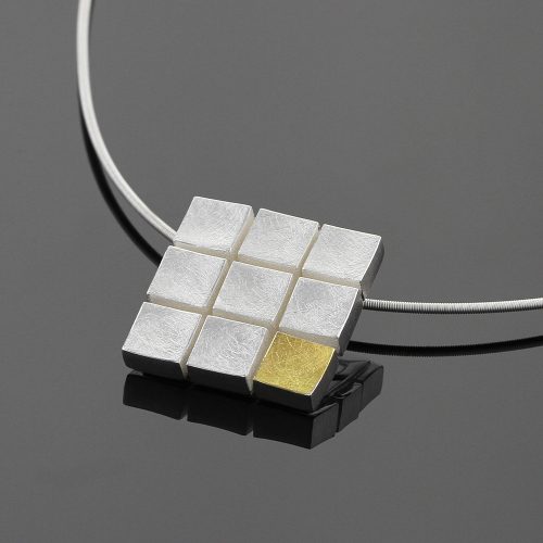 Square silver pendant made up of nine squares that seem to be floating. Eight of the squares are in a brushed silver whilst the bottom right square is in brushed gold.