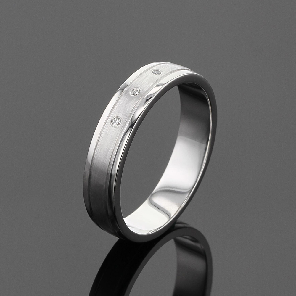 Simple wedding band in white gold with 3 diamonds in the center and two fine grooves seperating polished and matted surfaces.