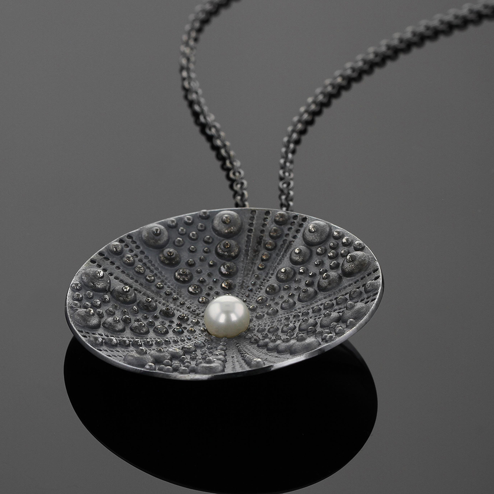 Large concave shaped disc pendant in black silver with sea urchin texture and a freshwater pearl