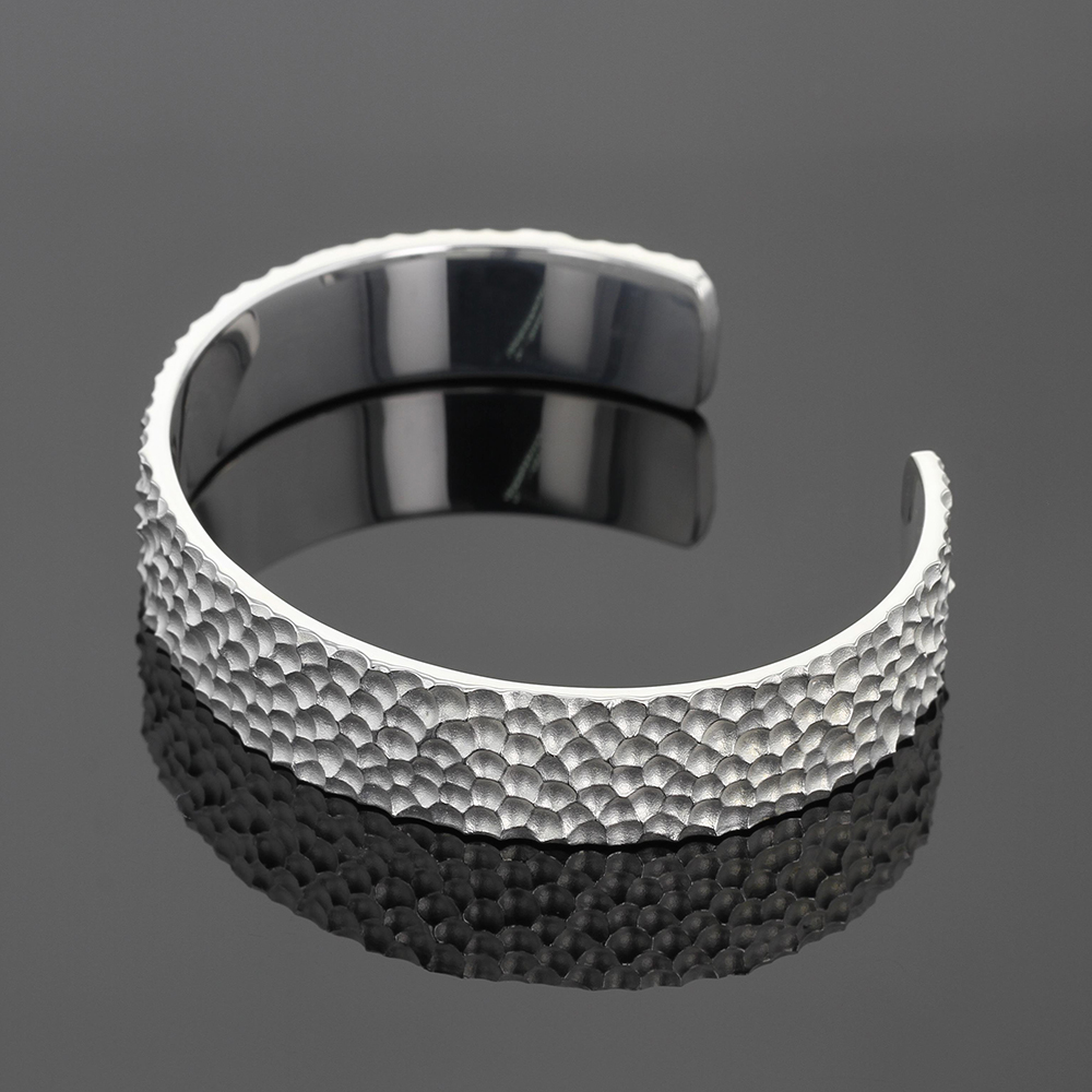 Wide bangle in silver with a rock inspired texture.