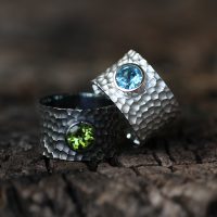 Wide silver rings with a lava rock texture and precious stones