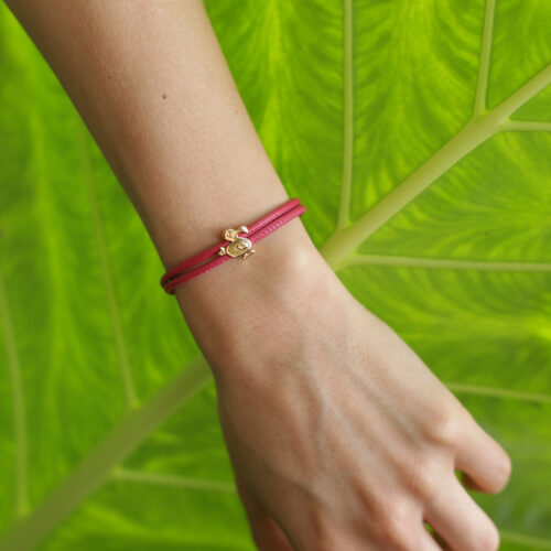 Polished rose gold dodo charm on a coral coloured leather bracelet.