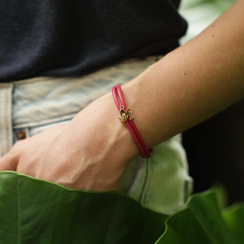 Polished rose gold dodo charm on a coral coloured leather bracelet.