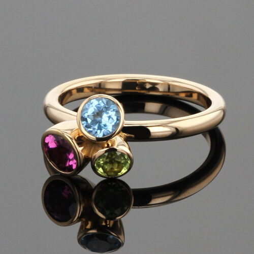 A beautiful trio of Peridot, Blue Topas and Rhodolite set in a 18ct rose gold ring