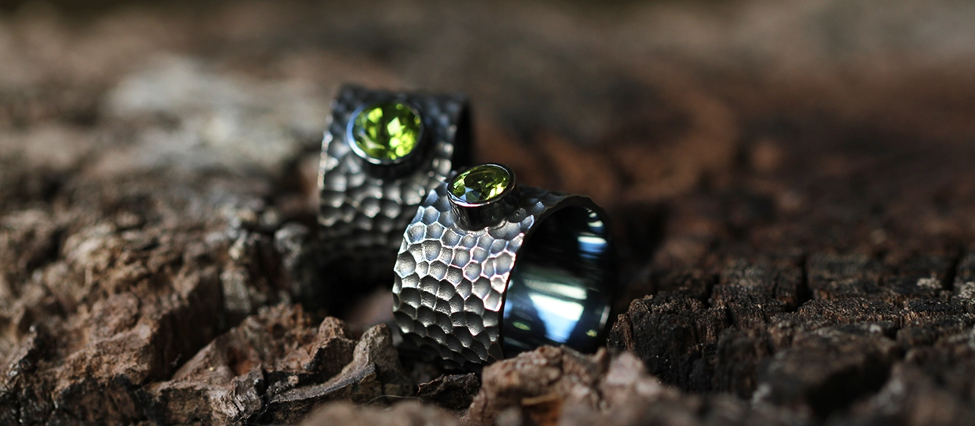 Black silver rings with a lava rock texture and Peridot stones