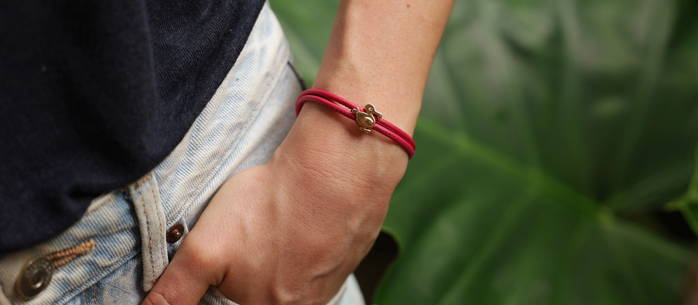 Rose gold dodo charm on a leather bracelet