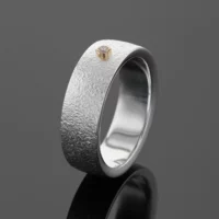 Textured silver ring with a yellow gold setting and diamond